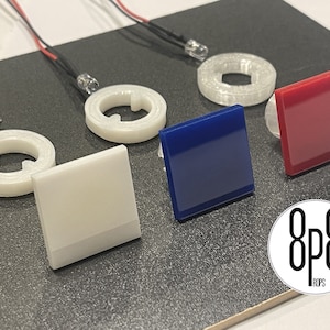 May include: An assortment of small, square, and circular components in white, blue, and red. The components are arranged on a dark surface, with small LED lights attached. The image also includes the logo "8p8 ROPS".