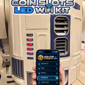 Puede incluir: Un kit WiFi LED para ranura de monedas R2-D2 con una carcasa robótica blanca y azul e indicadores de luz rojos verticales. Un teléfono inteligente muestra una interfaz de aplicación de control con opciones para diagnostics, rebel, imperial, hyperdrive, power surge y rainbow.