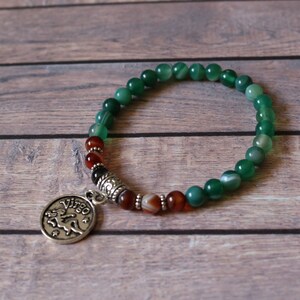 May include: A green and brown beaded bracelet with a silver Virgo zodiac charm.