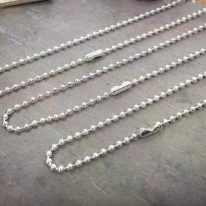 May include: Four silver ball chain necklaces of varying lengths, each with a silver clasp.