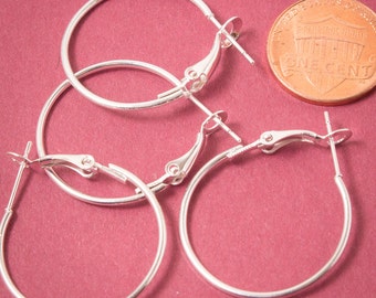 May include: Three silver hoop earrings with a hinged clasp. The earrings are approximately the size of a US penny.