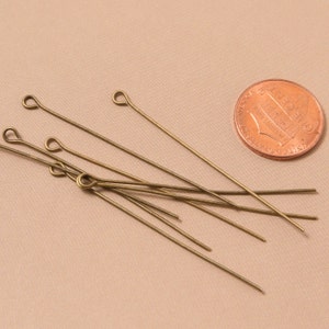 May include: A group of ten gold-toned head pins with a loop at one end. The pins are about the size of a US penny.