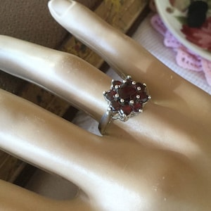 以下が含まれることがあります： 花の形に赤いガーネットがセットされたシルバーリングです。