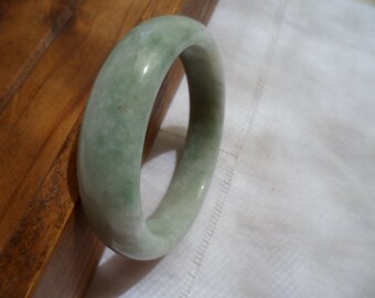 May include: A green jade bangle bracelet. The bracelet is smooth and polished.