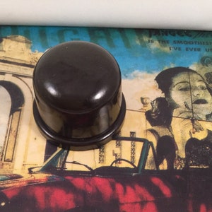 Puede incluir: Un recipiente redondo de plástico negro con una superficie lisa y brillante. El recipiente tiene una tapa y una base.