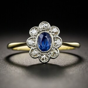 May include: A gold ring with a blue sapphire center stone surrounded by a halo of smaller diamonds.