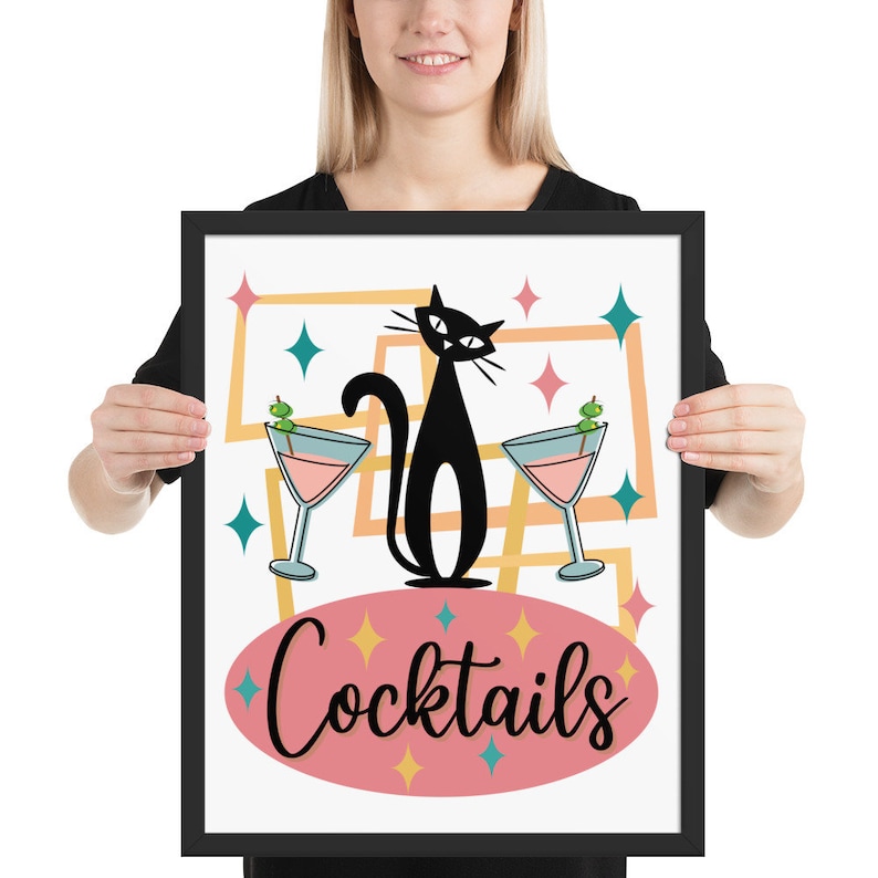 May include: A framed print with a retro design featuring a black cat with two martini glasses and the text "Cocktails". The background is a pink, yellow, and blue geometric pattern.