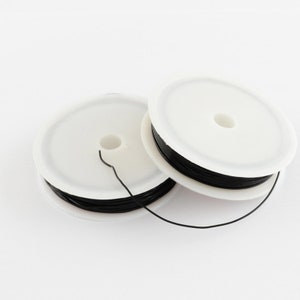 May include: Two spools of black wire on white plastic spools. The wire is thin and appears to be for jewellery making.