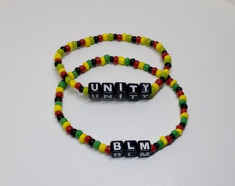May include: Two beaded bracelets with the words "UNITY" and "BLM" spelled out in black letter beads. The beads are red, yellow, and green.