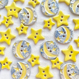 May include: A collection of yellow ceramic buttons featuring a crescent moon and star design. The buttons are decorated with blue and white paint.