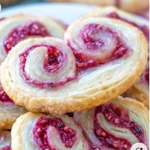 Peut inclure: Gros plan sur une pile de pâtisseries en forme de cœur avec une garniture de framboises roses. Les pâtisseries sont faites de pâte feuilletée et ont une couleur dorée.