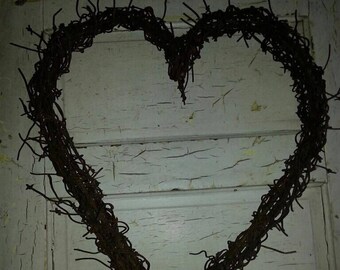 May include: A heart-shaped wreath made of barbed wire, hanging on a white painted door.