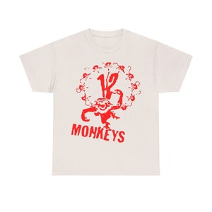 May include: A white t-shirt with a red graphic of a monkey with 12 monkeys surrounding it. The graphic says "12 Monkeys" in red.
