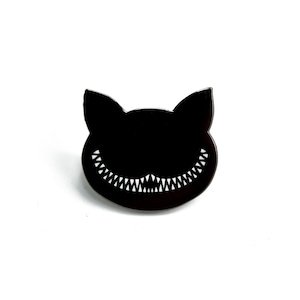 Può includere: Spilla in smalto nero con la silhouette di un gatto con un ampio sorriso pieno di denti.