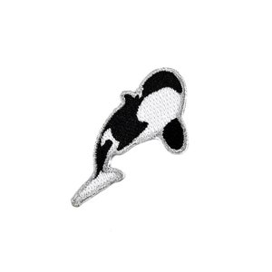 Könnte beinhalten: Schwarz-weiß gestickter Aufnäher einer Orca, oder Killerwal, der aus dem Wasser springt.
