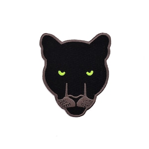 May include: Black panther head embroidered patch with green eyes.