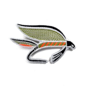 Könnte beinhalten: Gestickter Aufnäher, der ein stilisiertes Insekt darstellt, wahrscheinlich eine Fliegenfischer-Köder. Der Aufnäher hat olivgrüne Flügel mit schwarzen und orangefarbenen Akzenten und einen gebogenen Körper mit schwarz-weißen Details. Auf weißem Hintergrund.