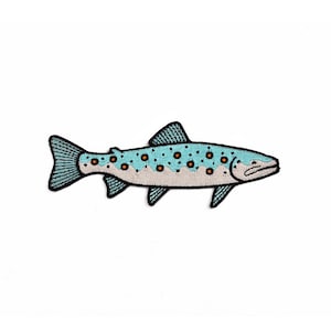 Op de afbeelding: Geborduurde patch van een vis met een lichtblauw lichaam, zwarte vinnen en een blauwgroene staart. De vis heeft kleine oranje stippen en een beige buik. De patch is waarschijnlijk voor kleding of accessoires.