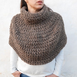 May include: A brown crocheted cowl neck poncho with a textured pattern.
