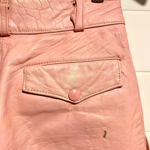 Puede incluir: Un pantal&oacute;n de cuero rosa con cintur&oacute;n y un bolsillo trasero. El pantal&oacute;n tiene cierre de bot&oacute;n y cremallera.