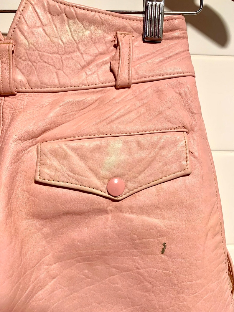 Puede incluir: Un pantal&oacute;n de cuero rosa con cintur&oacute;n y un bolsillo trasero. El pantal&oacute;n tiene cierre de bot&oacute;n y cremallera.