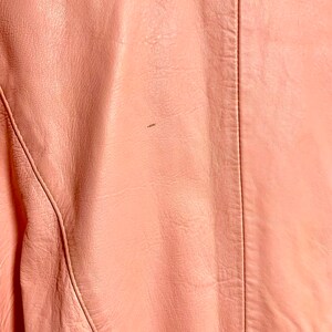 Puede incluir: Primer plano de una chaqueta de cuero rosa p&aacute;lido con una costura en la espalda.