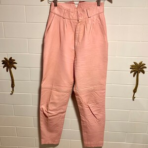 Puede incluir: Pantal&oacute;n de cuero rosa de cintura alta con cierre de bot&oacute;n. El pantal&oacute;n tiene una pierna recta y est&aacute; hecho de cuero suave y flexible.