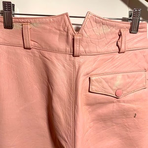 Puede incluir: Pantalones de cuero rosa con un bolsillo trasero y un cierre de bot&oacute;n. Los pantalones tienen una cintura en forma de V.