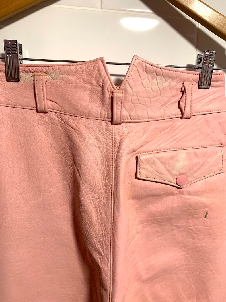 Puede incluir: Pantalones de cuero rosa con un bolsillo trasero y un cierre de bot&oacute;n. Los pantalones tienen una cintura en forma de V.