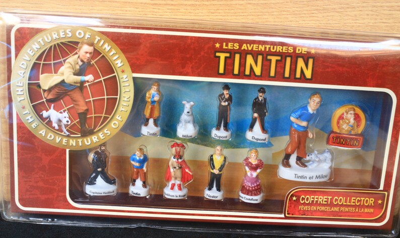 May include: A collector's set of porcelain figurines featuring characters from "The Adventures of Tintin." The set includes Tintin, Snowy, Captain Haddock, and other characters. The box has the title "Les Aventures de Tintin."