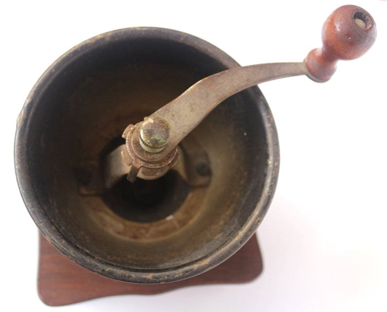 May include: A vintage wooden coffee grinder with a metal crank and a dark brown wooden base.