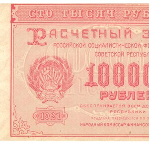 May include: A vintage Russian banknote with a red background and the text "СТО ТЫСЯЧ РУБЛЕЙ" (One Hundred Thousand Rubles) in large, bold letters. The note features a coat of arms with a hammer and sickle, wheat stalks, and the year "1921".