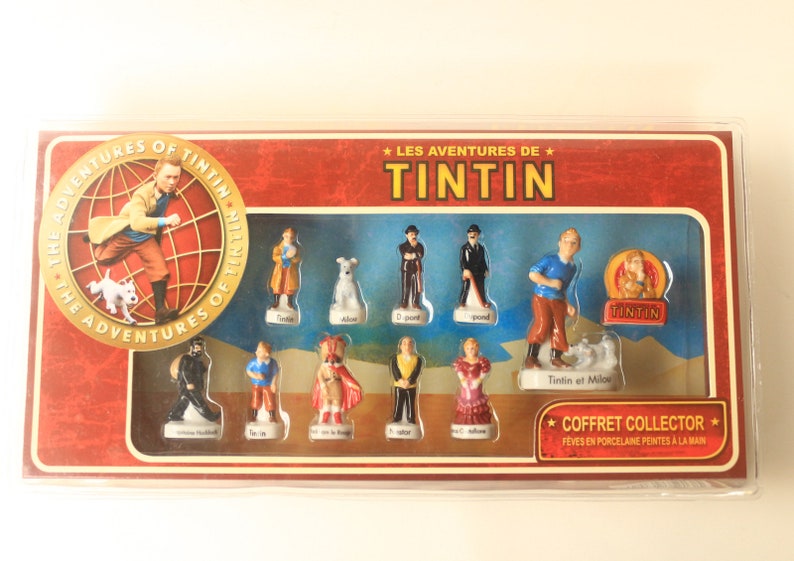 May include: A collector's set of porcelain figurines featuring characters from "The Adventures of Tintin." The set includes Tintin, Snowy, Captain Haddock, and other characters. The box has the title "The Adventures of Tintin."