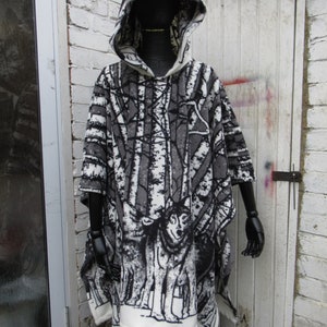 May include: A white and gray hooded poncho with a wolf print. The poncho has a black and white forest scene with trees and wolves.
