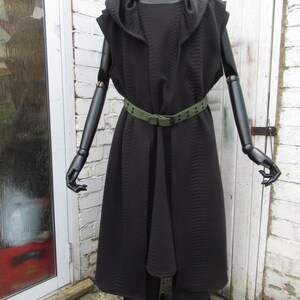 May include: A black hooded coat and matching pants are displayed on a mannequin. The coat features a quilted texture, a draped front, and a green belt. The outfit is styled on a black mannequin with articulated arms and hands.