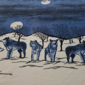 May include: A white and blue fleece blanket with a design of wolves howling at the moon. The blanket features a white background with a blue sky and trees. The wolves are blue and white.