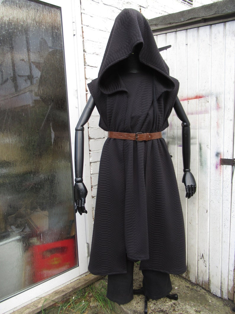 May include: A black hooded cloak and matching pants displayed on a mannequin. The cloak features a quilted pattern and is cinched at the waist with a brown belt. The mannequin has black articulated arms and hands.