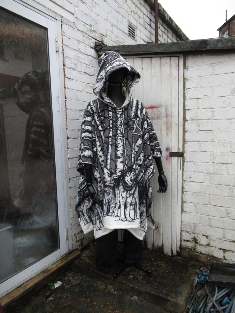 May include: A black and white hooded poncho with a forest scene print. The poncho is made of a soft, fuzzy fabric and has a drawstring hood.