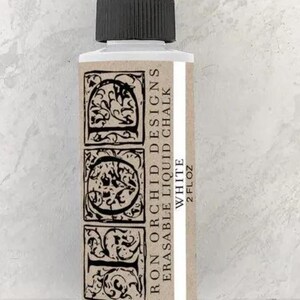 May include: A white bottle of Iron Orchid Designs erasable liquid chalk with a black cap. The label features ornate black lettering and designs. The bottle contains 2 fl oz of white chalk.