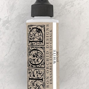 May include: A 2-ounce bottle of Iron Orchid Designs Erasable Liquid Chalk in white. The bottle has a black cap and a label with the brand name and product information.