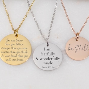 May include: Three round pendant necklaces with inspirational quotes. One is gold-toned with the quote "You are braver than you believe." The second is silver-toned with the quote "I am fearfully & wonderfully made." The third is rose gold-toned with the quote "be Still."