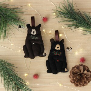May include: Two felt black bear ornaments with red berries and green leaves. The ornaments are numbered #1 and #2.
