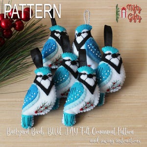 以下が含まれることがあります： 黒いリボンが付いた、6つのフェルト製の青い鳥のオーナメント。鳥は白、青、黒のディテールで、小さな赤いベリーのアクセントが付いています。「PATTERN」という文字が左上にあり、下部には「Backyard Birds BLUE JAY Felt Ornament Pattern and sewing instructions」と書かれています。