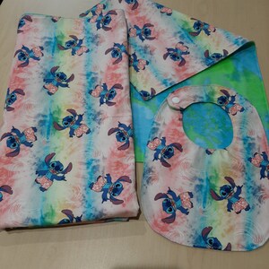 Puede incluir: Un juego de manta, pa&ntilde;o de eructo y babero para beb&eacute;. Los art&iacute;culos presentan un patr&oacute;n repetido de un personaje de dibujos animados azul con pantalones cortos rosas sobre un fondo te&ntilde;ido anudado de color rosa, azul, amarillo y verde. El babero tiene un cierre a presi&oacute;n.