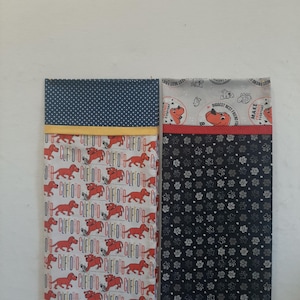 May include: Two rectangular fabric pillowcases. The left one features a white background with red Clifford the Big Red Dog illustrations, the text Clifford, and a navy blue polka dot top border. The right one has a black background with white paw prints and a light gray top border with Clifford graphics and text.