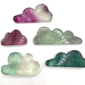 May include: Five polished fluorite crystal cloud shapes in various shades of green, pink, and white. The crystals are smooth and have a translucent appearance.