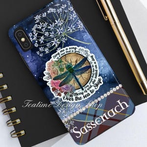 May include: A blue and white phone case with a dragonfly, a compass, and flowers. The case has a quote that reads "Sing me a song of a lass that is gone. Merry of soul, she sailed on a day. Say, could that lass be off? Over the sea to Skye." The case also has a plaid pattern with the word "Sassenach" on it.