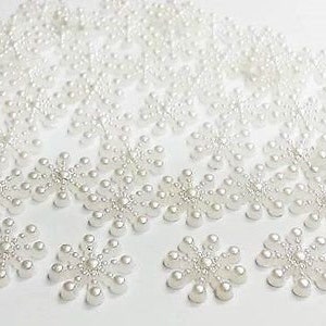 Peut inclure: Une collection de décorations en forme de flocon de neige en perles blanches. Chaque flocon de neige est composé de petites perles rondes disposées en forme d'étoile à six branches.