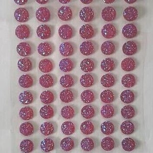 May include: A sheet of pink iridescent adhesive gems, each gem is about 1 cm in diameter.