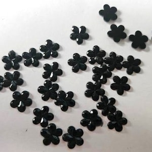 May include: A collection of black flower-shaped embellishments, perfect for adding a touch of sparkle to crafts and DIY projects.